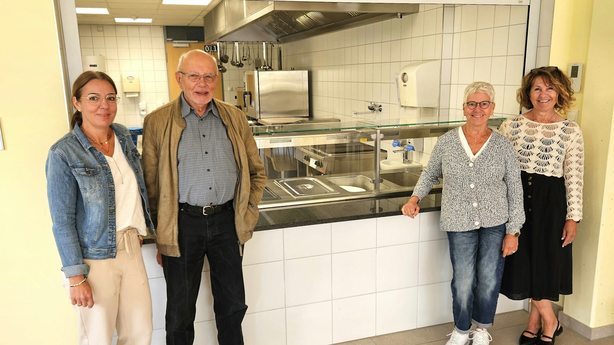Simone Crombach, Hans Reiff, Ursula Möres und Marianne Rütt stehen vor der Ausgabentheke der Küche.
