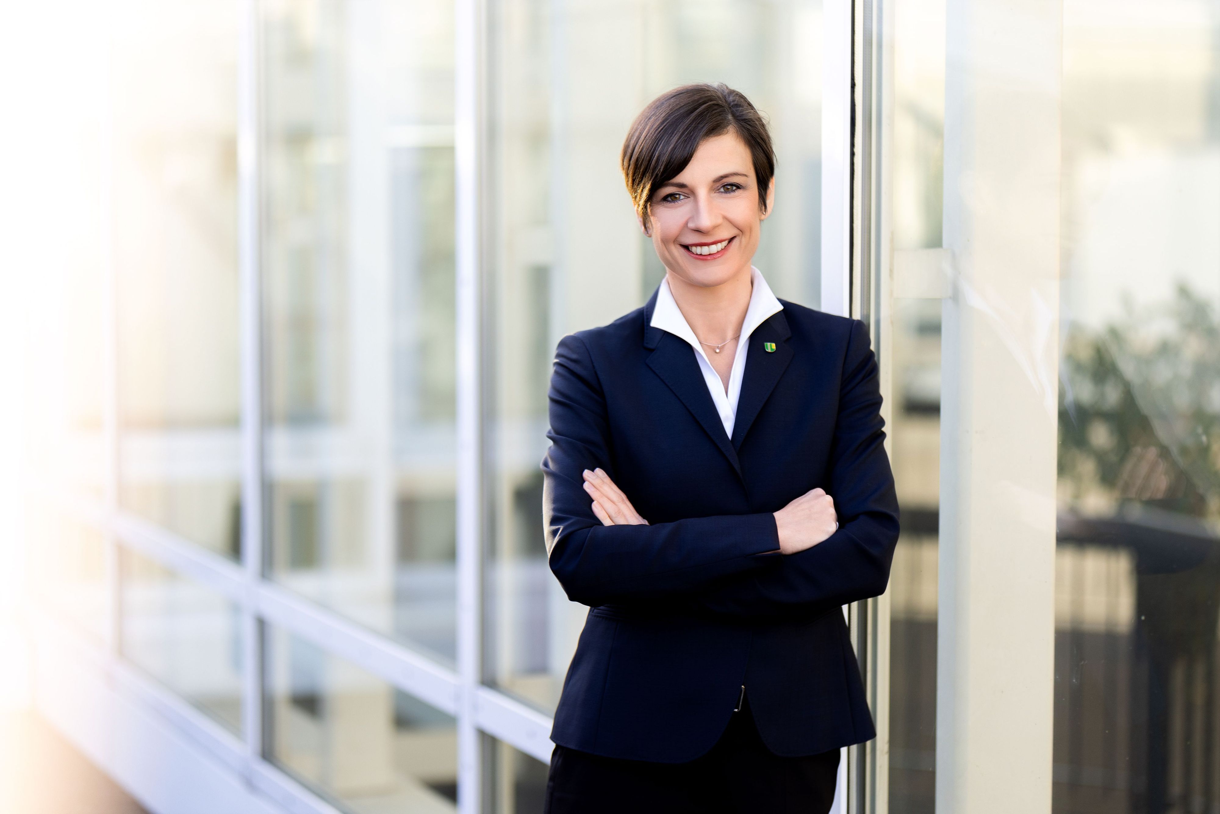 Eine Frau steht vor einer Fensterfront.