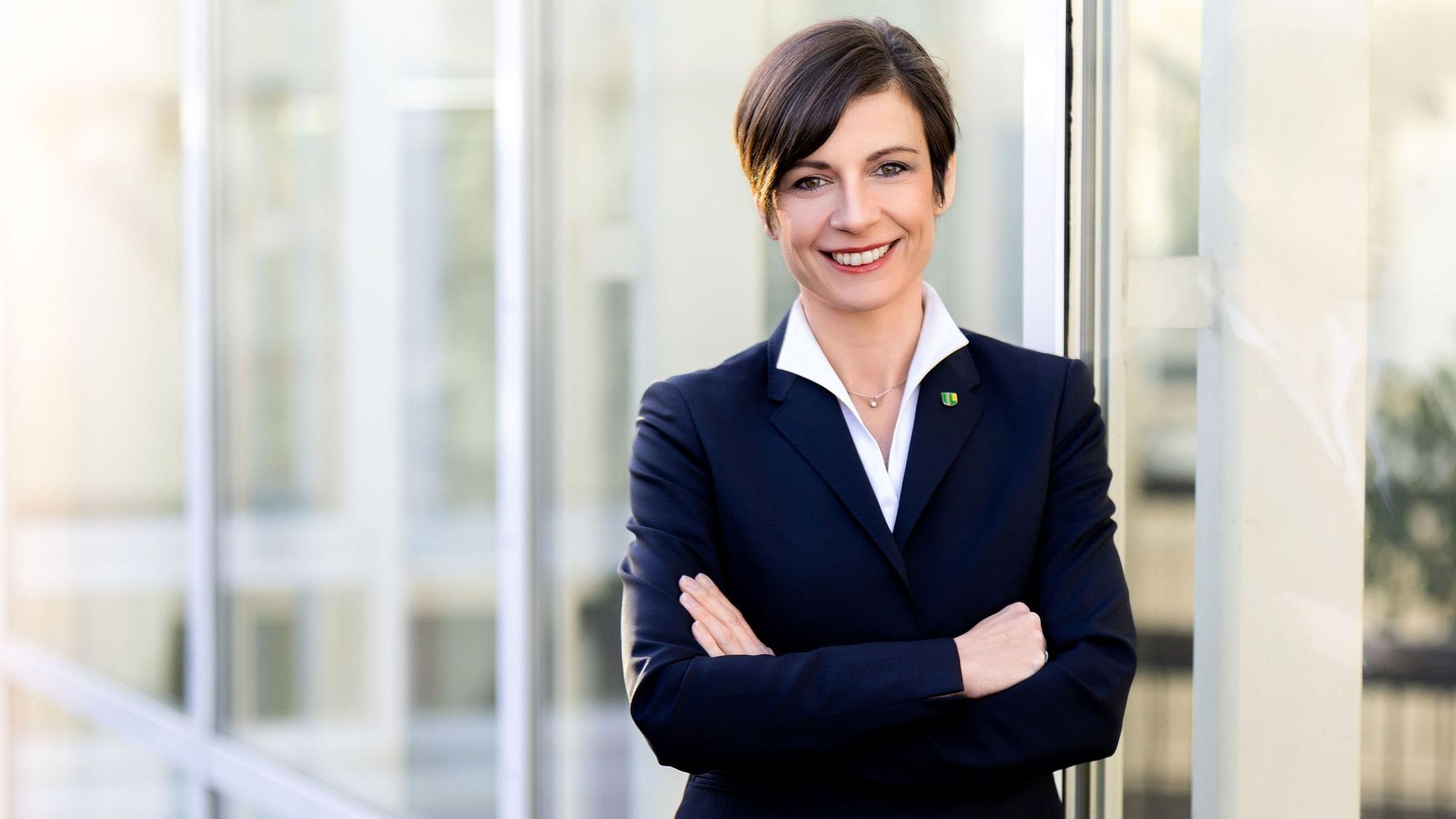 Eine Frau steht vor einer Fensterfront.