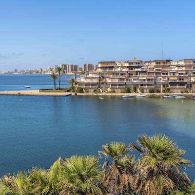 Das Stadtbild von La Manga im Sommer, mit dem ruhigen blauen Meer, den sich wiegenden Palmen und dem malerischen Blick auf die Küste.