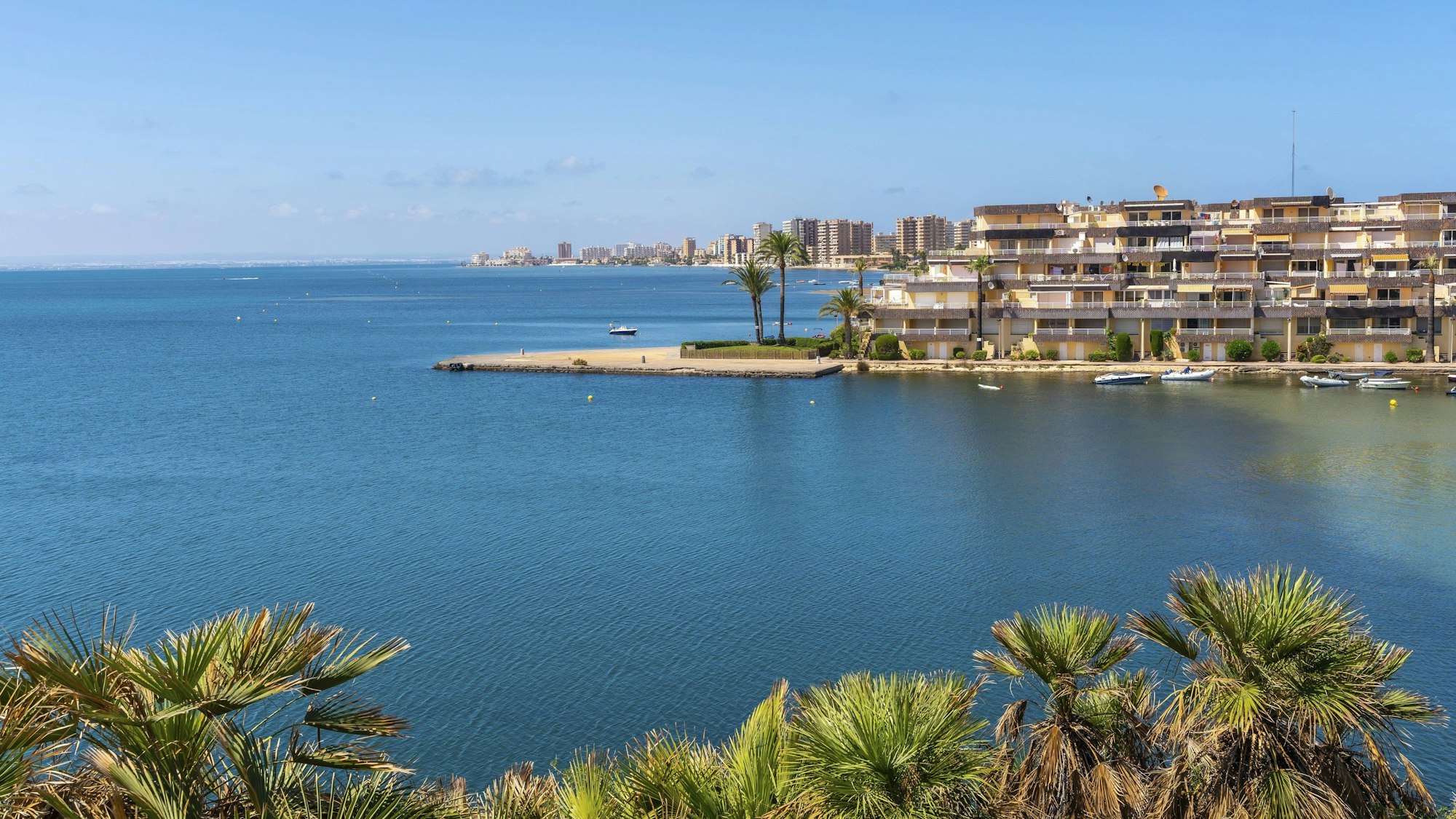 Das Stadtbild von La Manga im Sommer, mit dem ruhigen blauen Meer, den sich wiegenden Palmen und dem malerischen Blick auf die Küste.