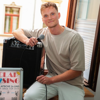 Der Kölner Sänger Savoy sitzt auf seiner Fensterbank und bereitet sich auf sein Fensterkonzert unter dem Titel Clap2Sing vor.