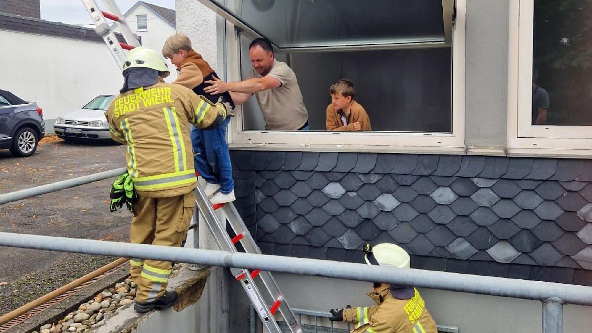 Ein Mann hilft einem Kind beim Abstieg über eine Feuerwehrleiter.