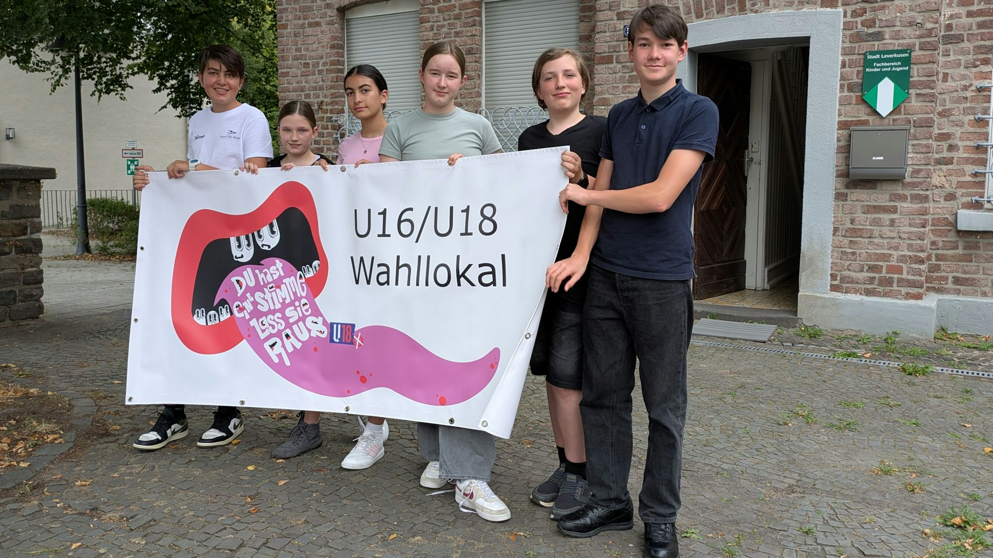 Sechs Jugendliche halten ein Transparent für die U-16-Wahl hoch.