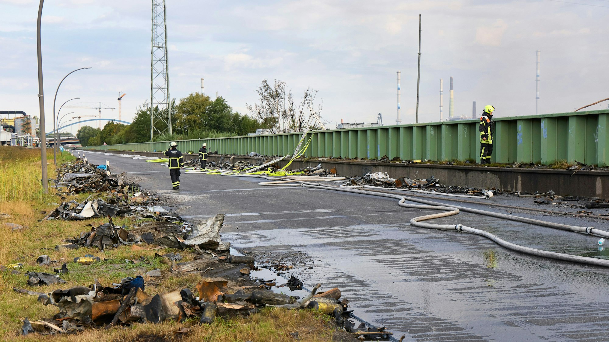 Einsatzkräfte der Feuerwehr löschen einen Brand in einem Industriegebiet im Hamburger Hafen während Trümmerteile auf der Straße liegen. In der Nacht zu Mittwoch ist es erneut zu Explosionen gekommen.