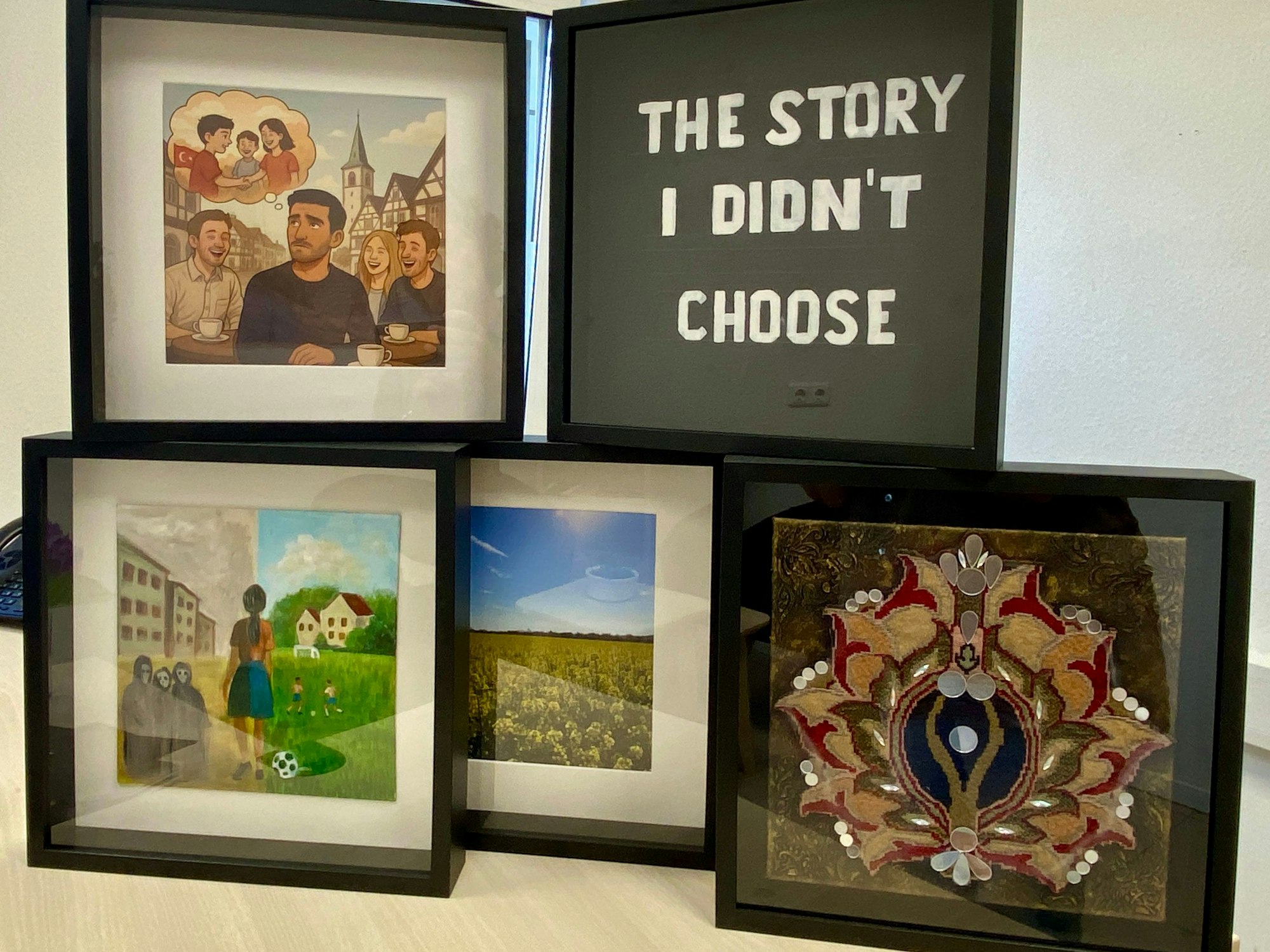 Fünf viereckige schwarze Bilderrahmen stehen neben- und übereinander. Darin zu sehen sind einige der Kunstwerke, die beim Projekt "Heimat in NRW "entstanden sind.