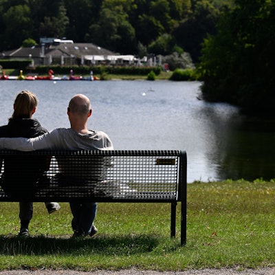 Köln: Ein Mann und eine Frau sitzen im Kölner Grüngürtel auf einer Parkbank.