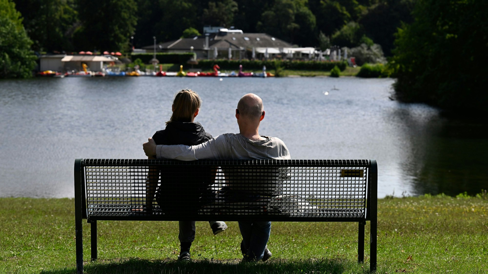 Köln: Ein Mann und eine Frau sitzen im Kölner Grüngürtel auf einer Parkbank.
