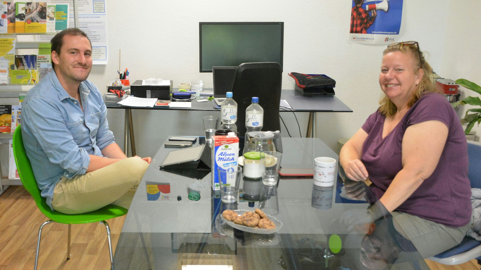 Ein Mann und eine Frau sitzen an einem Glastisch.