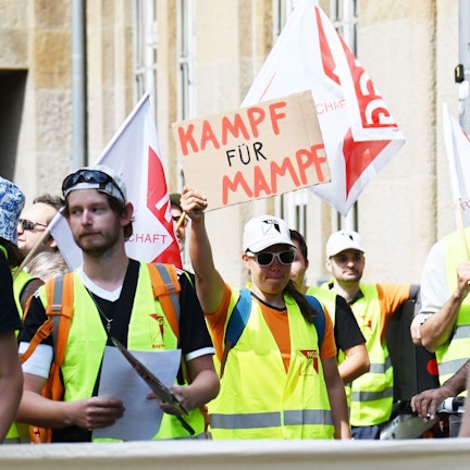 Demonstrierende gehen durch Köln. Eine Teilnehmerin hält ein Schild in der Hand mit der Aufschrift: „Kampf für Mampf“.