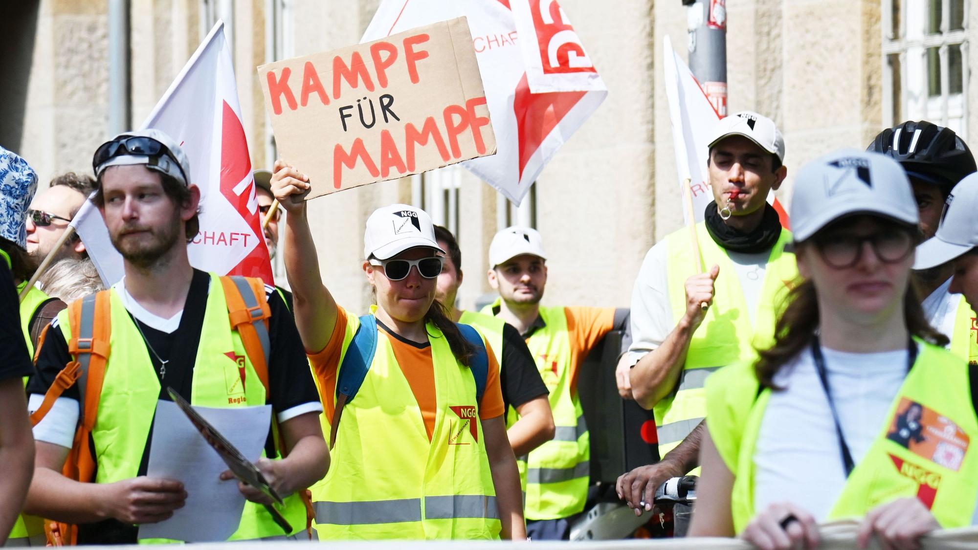 Demonstrierende gehen durch Köln. Eine Teilnehmerin hält ein Schild in der Hand mit der Aufschrift: „Kampf für Mampf“.