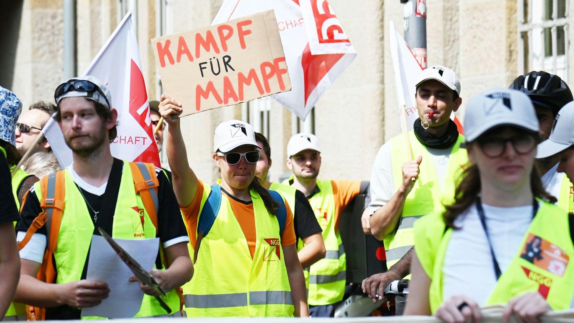 Demonstrierende gehen durch Köln. Eine Teilnehmerin hält ein Schild in der Hand mit der Aufschrift: „Kampf für Mampf“.