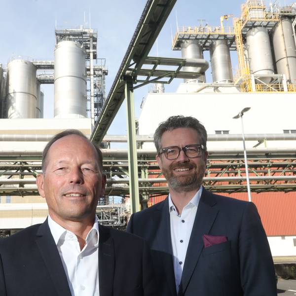 Gruppenbild mit Thomas Bastel, Thomas Wessel und Arndt Selbach. Alle tragen dunkle Anzüge ohne Krawatte. Im Hintergrund sind Chemieanlagen zu sehen.