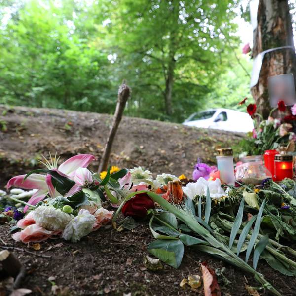Blumen und Kerzen stehen an einem Baum in einer Kurve der Dürschtalstraße, in der am 16. August 2025 vier Teenager bei einem Unfall ums Leben kamen.