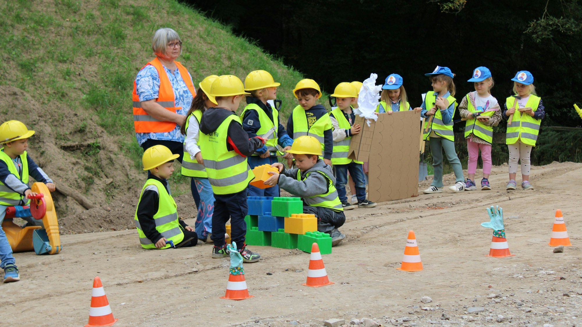 Mit Wasserwaage nachgemessen: Kita-Kinder stellen beim Spatenstich die einzelnen Bauabschnitte dar.