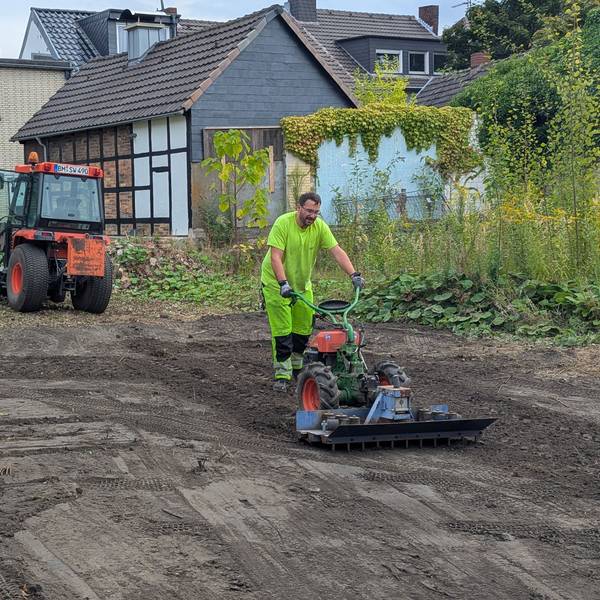 Das Foto zeigt einen Mitarbeiter der Stadtwerke beim Bearbeiten des Bodens, im Hintergrund ein Bagger.