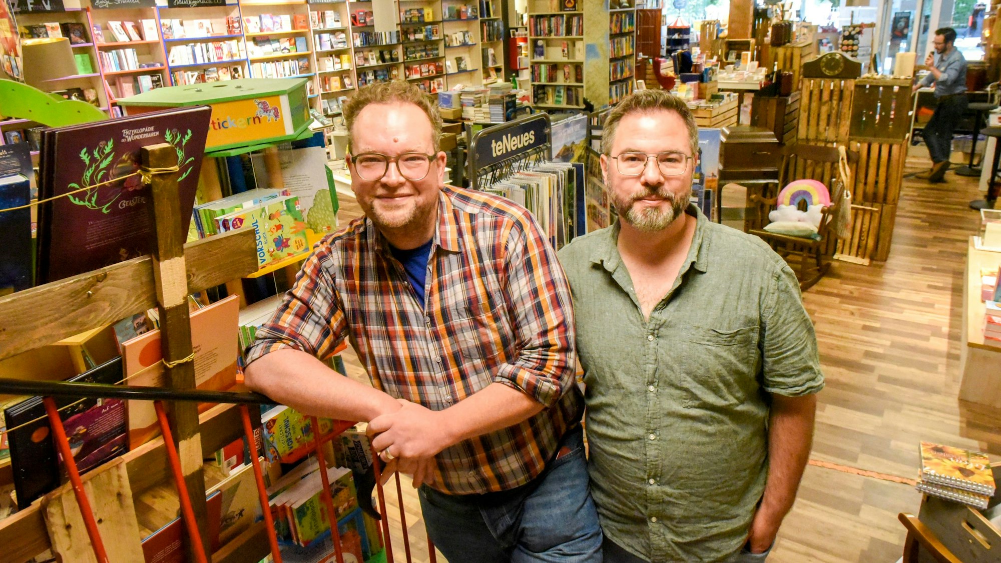 Das Foto zeigt die beiden Inhaber der Buchhandlung vor Bücherregalen in ihrem Geschäft.