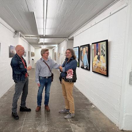Drei der neuen Künstler des Vereins im Gang des Künstlerbunkers. Michael Brock (v.l.), Thomas Ernst und Norbert Küpper. An den Wänden hängen die Werke der Ausstellung.