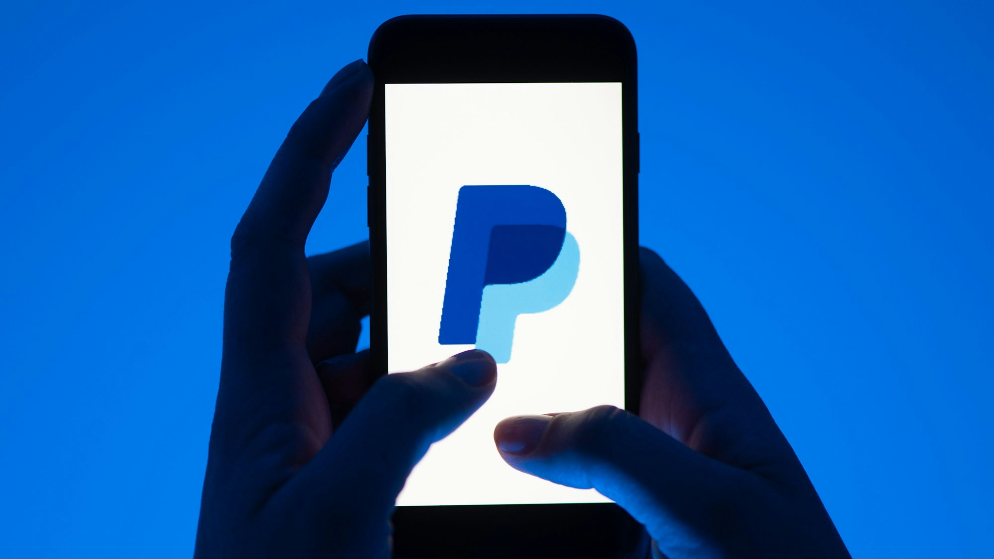 ARCHIV - 12.05.2022, Sachsen, Dresden: Eine Frau hält ein Smartphone mit dem Logo des Bezahldienst Paypal. (gestellte Szene) (zu dpa: «Bezahlen in Echtzeit: ING führt Paypal-Konkurrent Wero ein») Foto: Sebastian Kahnert/dpa +++ dpa-Bildfunk +++