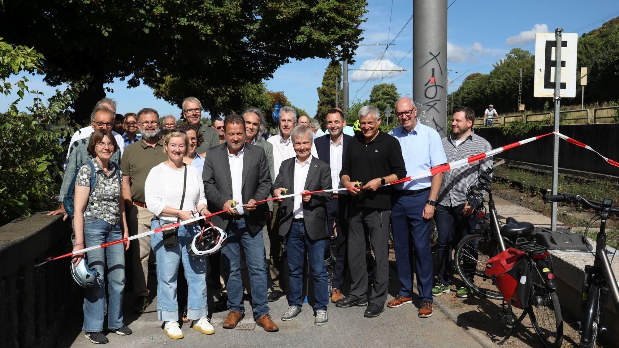 Eine große Gruppe Menschen hinter einem rot-weißen Absperrband.