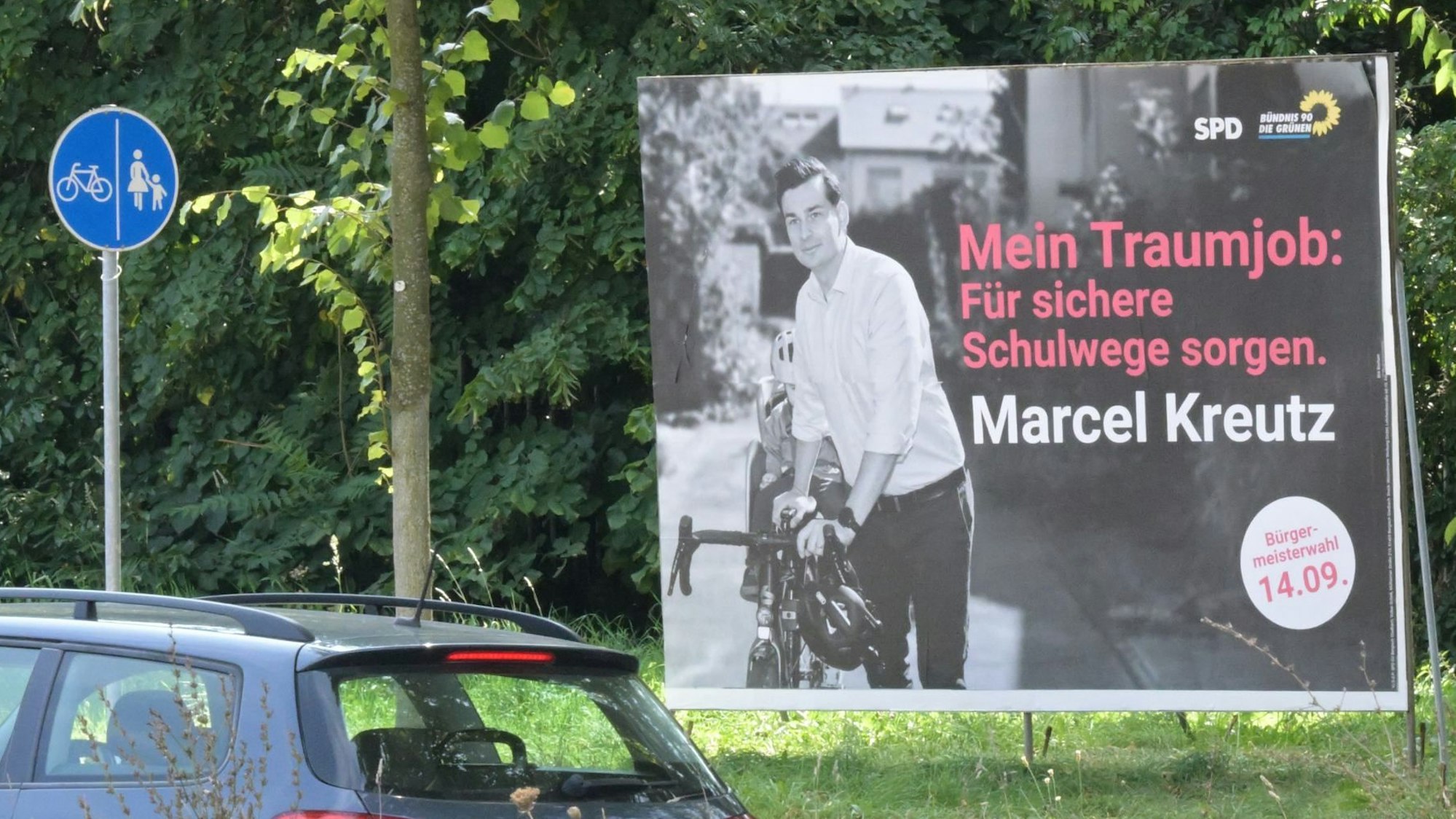 Die Wahlplakate des SPD-Bürgermeisterkandidaten Marcel Kreutz stehen direkt am Radweg. Darauf steht: „Mein Traumjob: Für sichere Schulwege sorgen.“