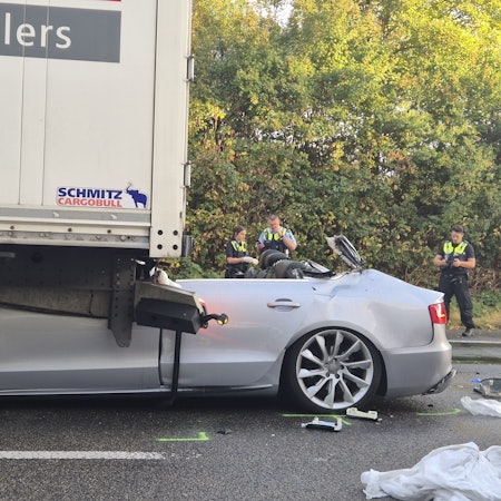 Ein Pkw steht nach einem tödlichen Unfall unter einem Lkw. Foto: Sascha Thelen/dpa