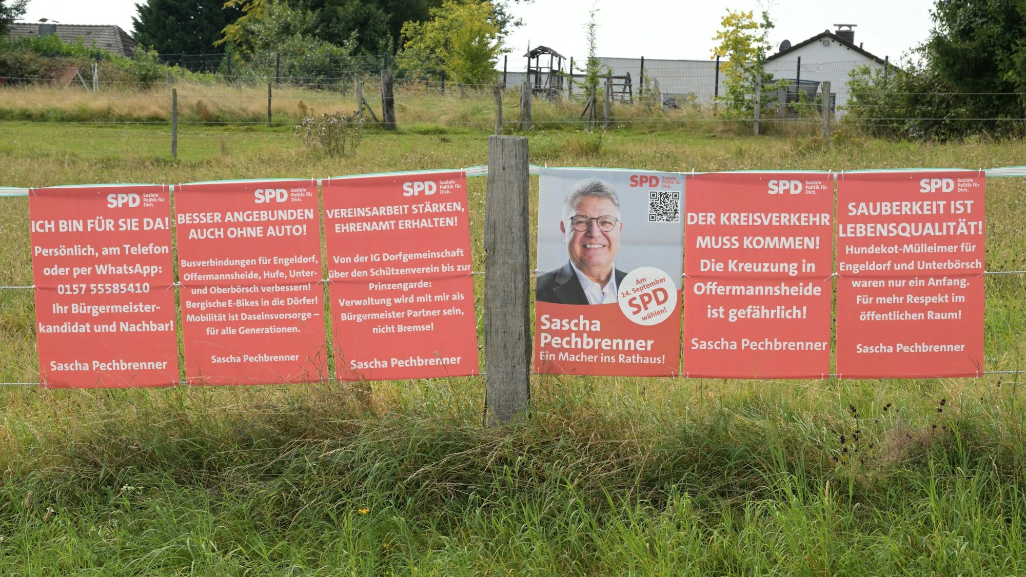 SPD-Bürgermeisterkandidat Sascha Pechbrenner hängt mehrere Plakate nebeneinander, auf denen seine Vorschläge für Kürten stehen.