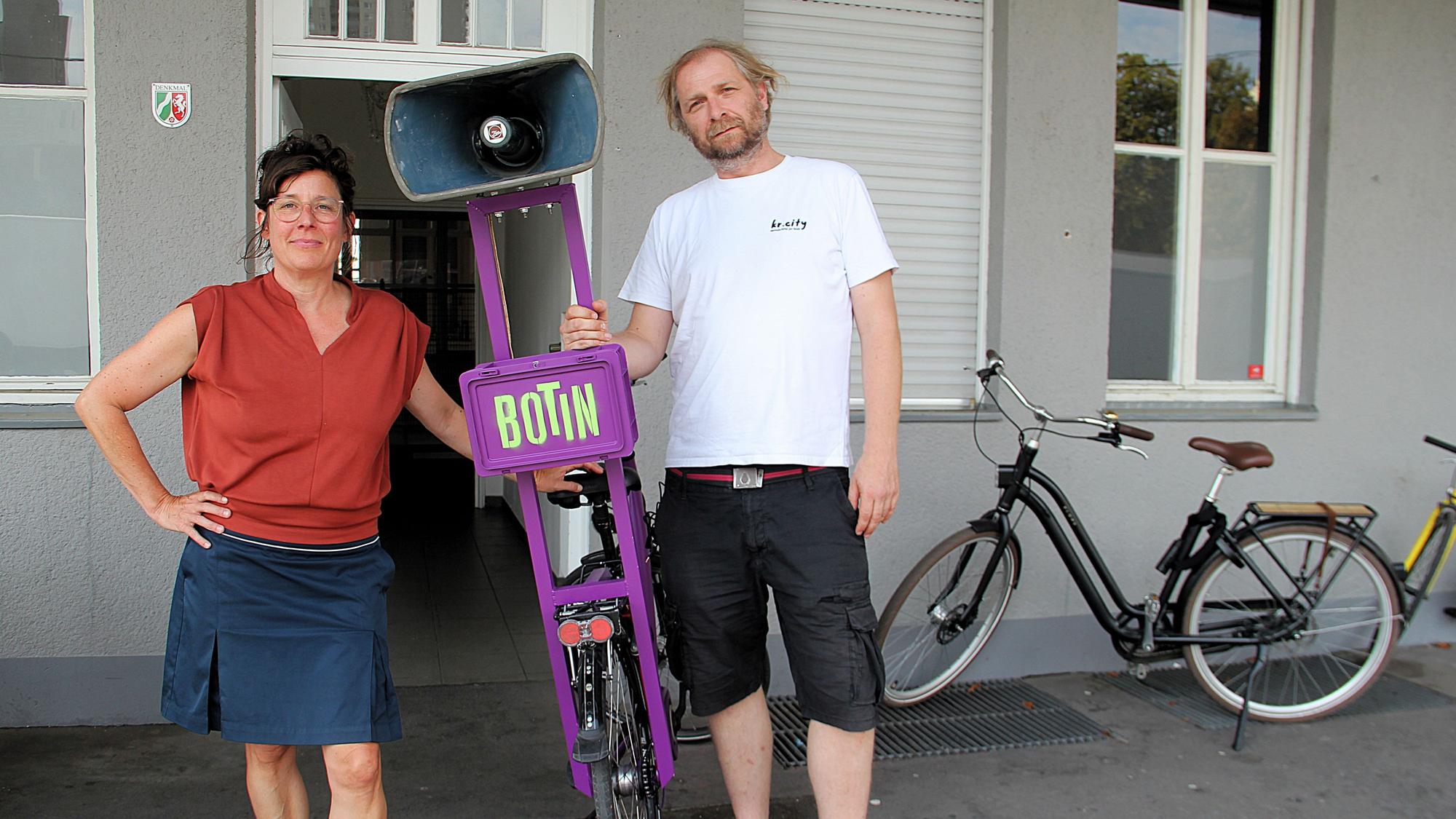 Eine Frau und ein Mann stehen nebeneinander, zwischen ihnen ein Fahrrad mit einem ungewöhnlichen Gepäckträger.