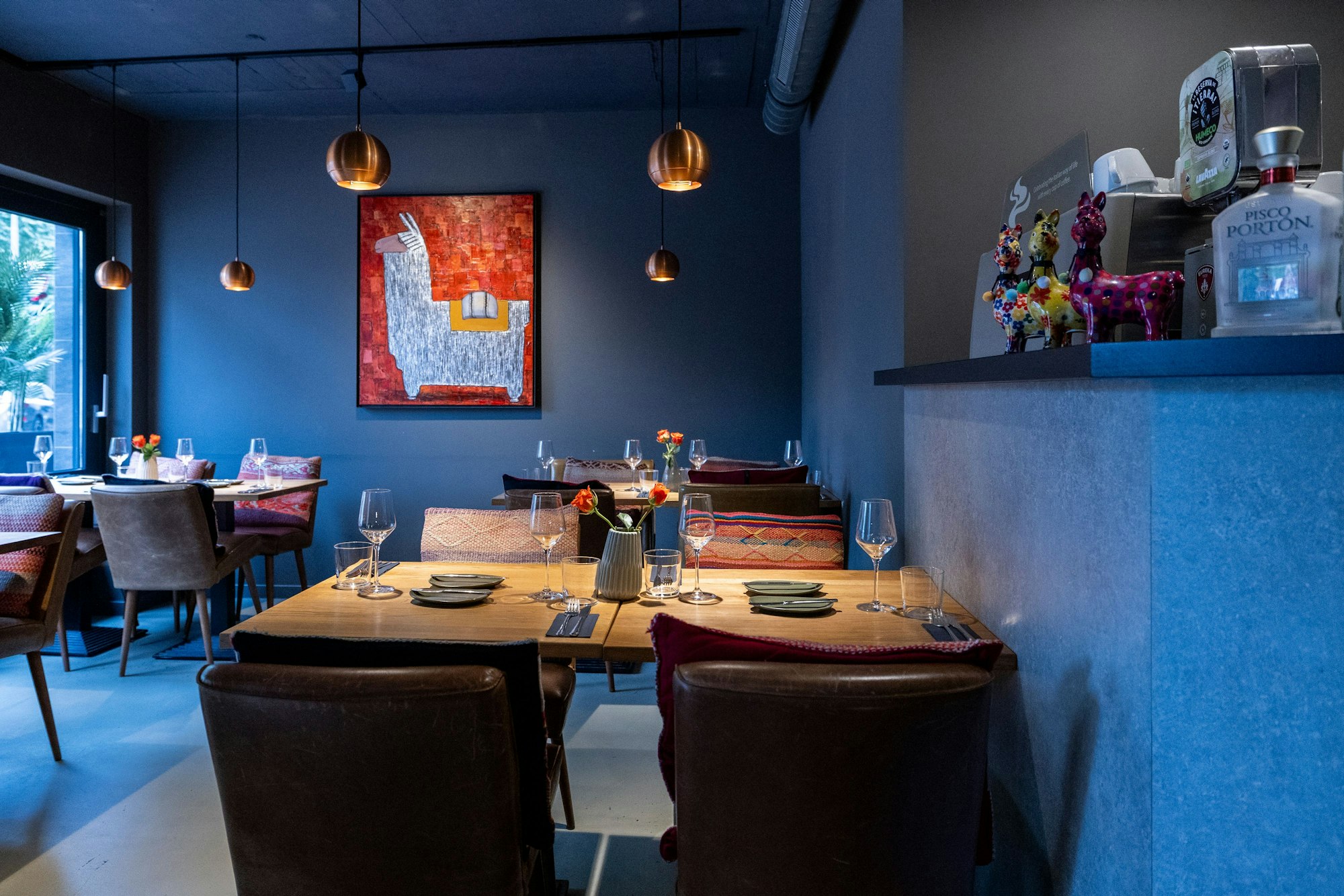 Das Restaurant „Flor y Canela“ innen ist zu sehen. Auf einem Bild and er Wand ist ein Lama vor orangenem Hintergrund gemalt.