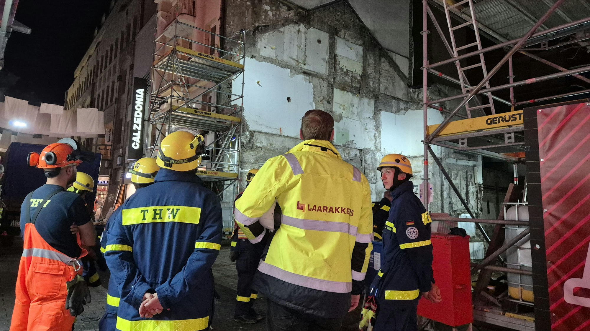 Einsatzkräfte vom Technischen Hilfswerk (THW) und einer Baufirma stehen vor einer Hauswand, die möglicherweise einsturzgefährdet sei, hieß es vom Lagedienst der Feuerwehr.