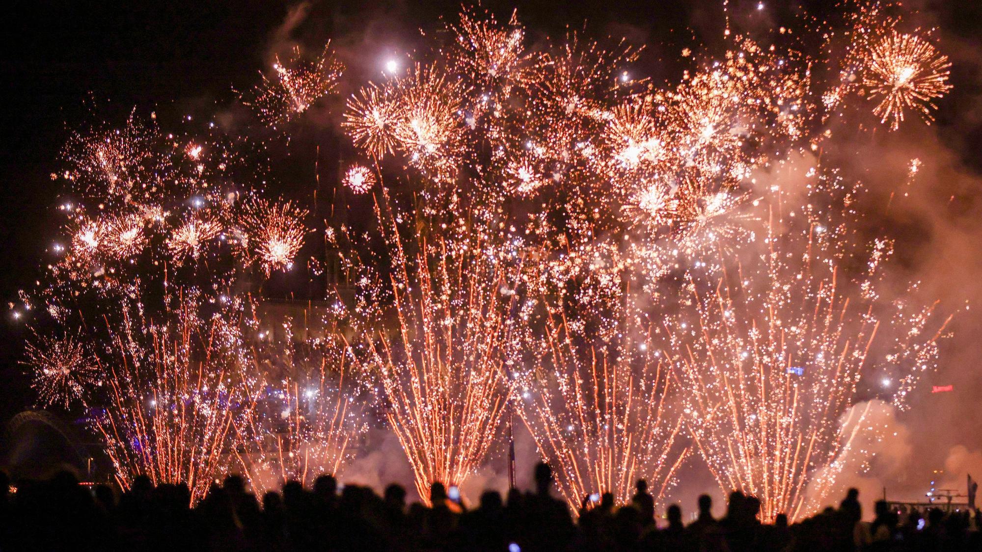 Menschen besuchen im Kölner Rheinpark das größte musiksynchrone Feuerwerk Europas.