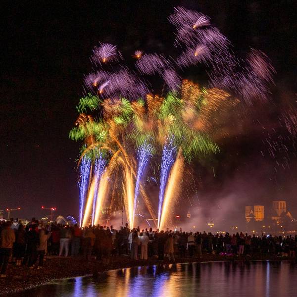 Menschen besuchen im Kölner Rheinpark das größte musiksynchrone Feuerwerk Europas.
