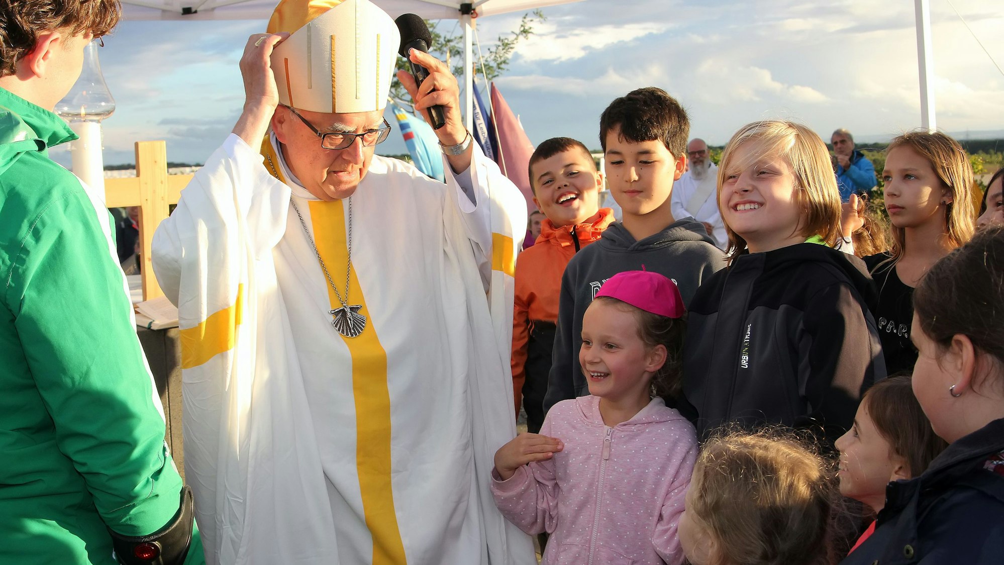 Auf dem Bild ist ein Bischof zu sehen, der seine Insignien einer Gruppe von Kindern erklärt.
