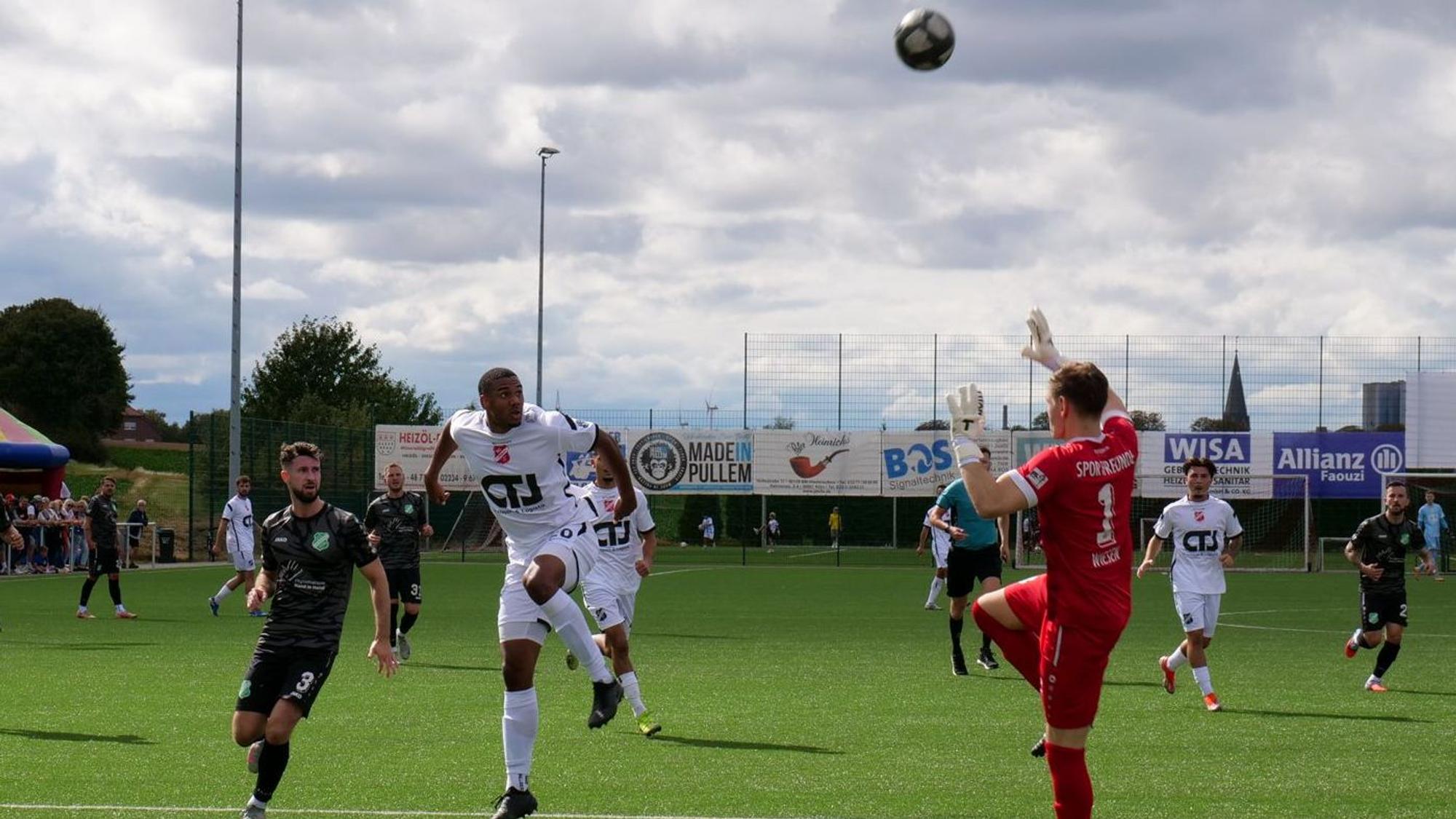 Das Foto zeigt einen Fußballer in Weiß, der den Ball über den heranstürmenden Torhüter lupft.