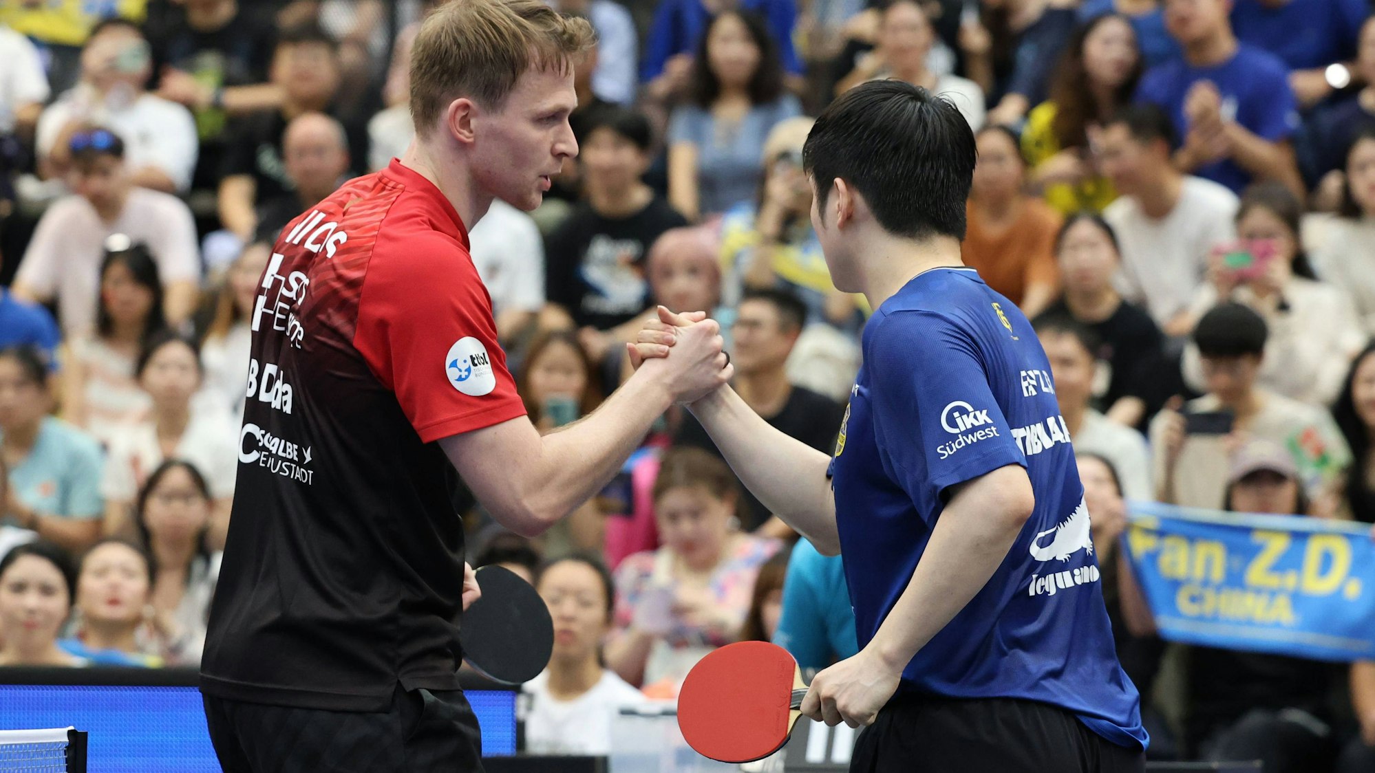 Fan Zhendong und Benedikt Duda reichen sich nach dem Spiel die Hand.