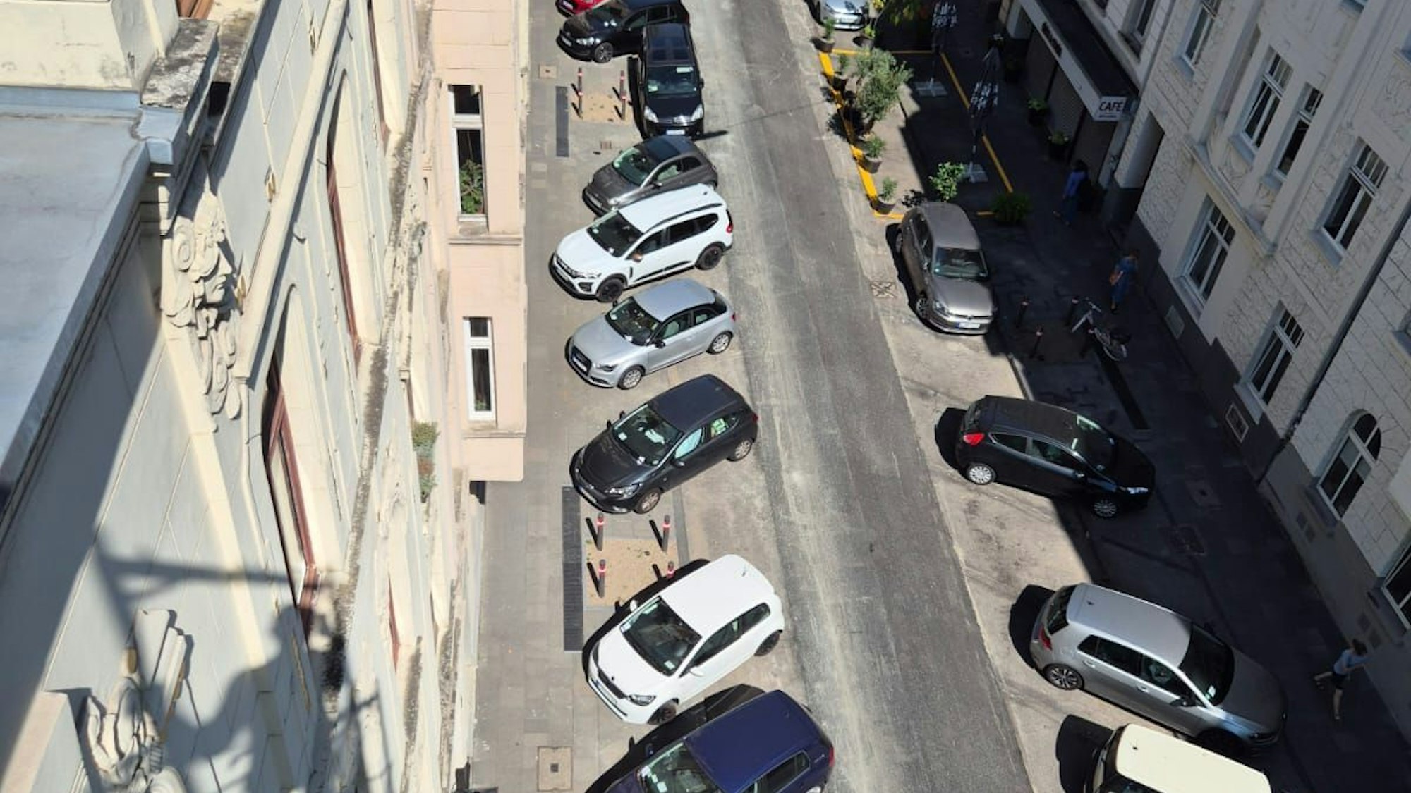 Quer zur Fahrbahn geparkte Autos mit Strafzetteln an der Windschutzscheibe in einer Kölner Straße.