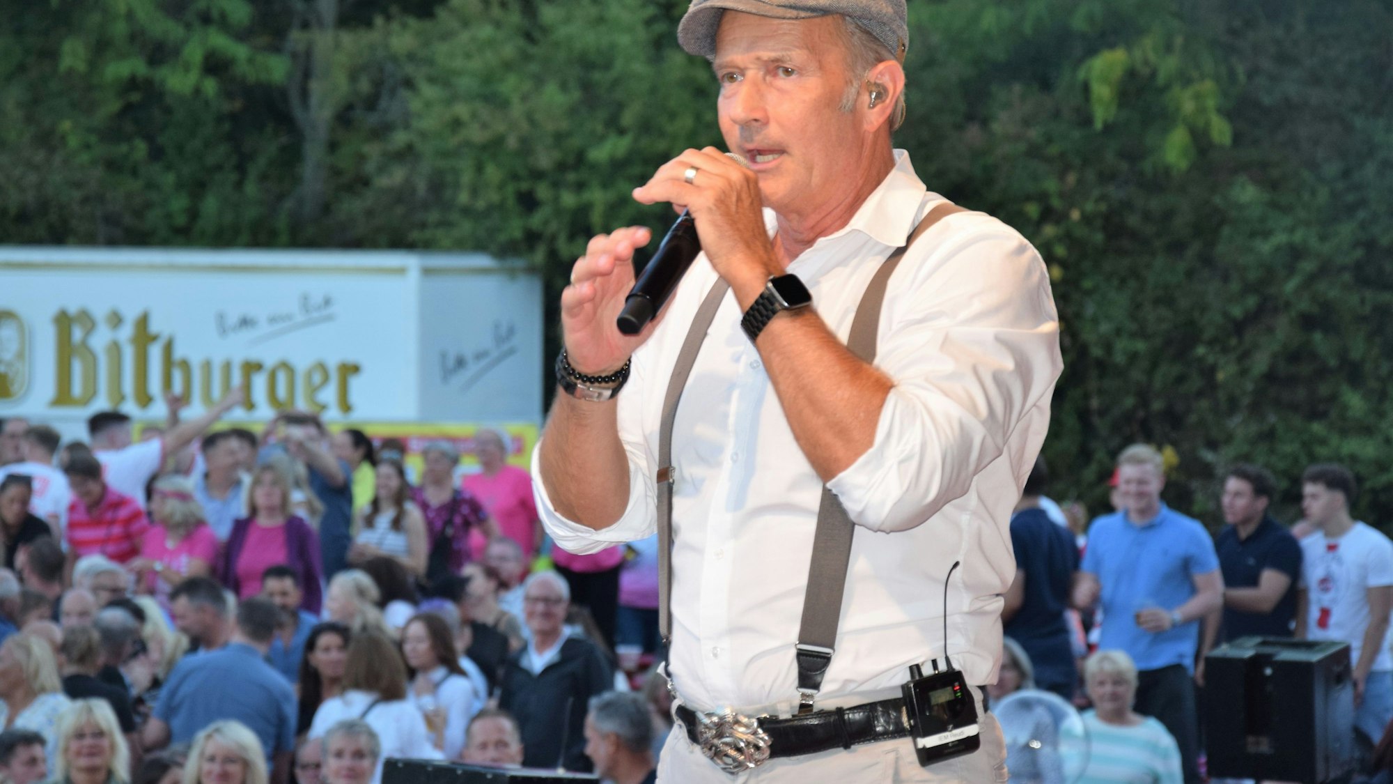 Auf dem Bild ist ein Sänger auf der Bühne vor Publikum zu sehen.