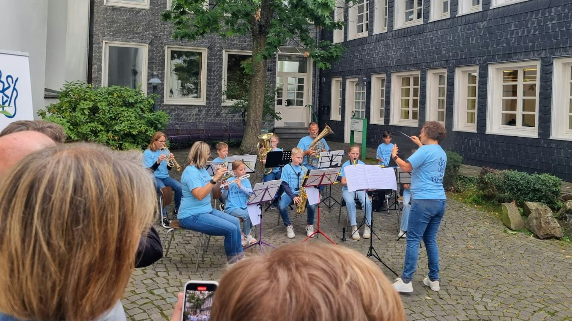 Ein Orchester spielt unter freiem Himmel vor einem Gebäude.