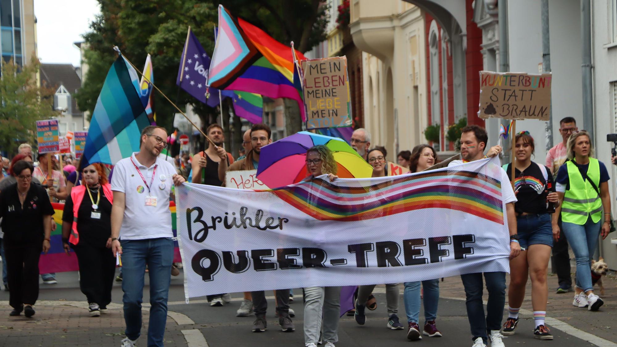 Zu sehen ist der Demonstrationszug, an dessen Spitze Menschen ein Banner hochhalten.