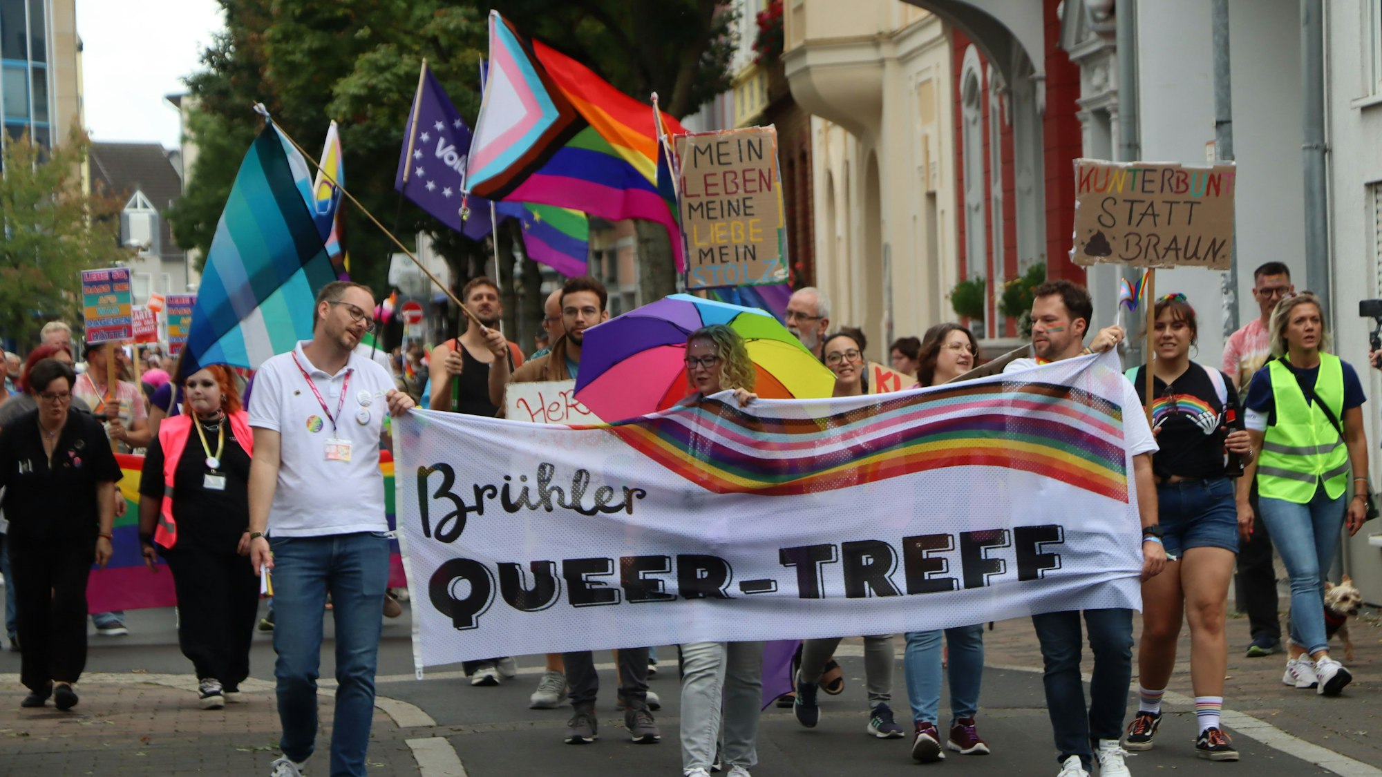 Zu sehen ist der Demonstrationszug, an dessen Spitze Menschen ein Banner hochhalten.