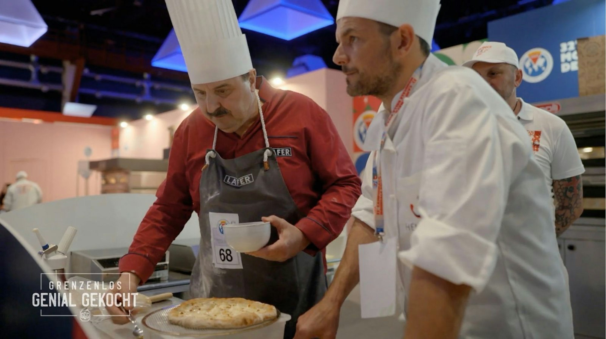 Der erste Wettkampf. Steffen Henssler (rechts) und Johann Lafer treten in der Klasse „Pizza a due“ im Team an. Kommt ihre ausgefallene Idee bei der Jury an? Sie machen „Pizza Carbonara“. (Bild: RTL)