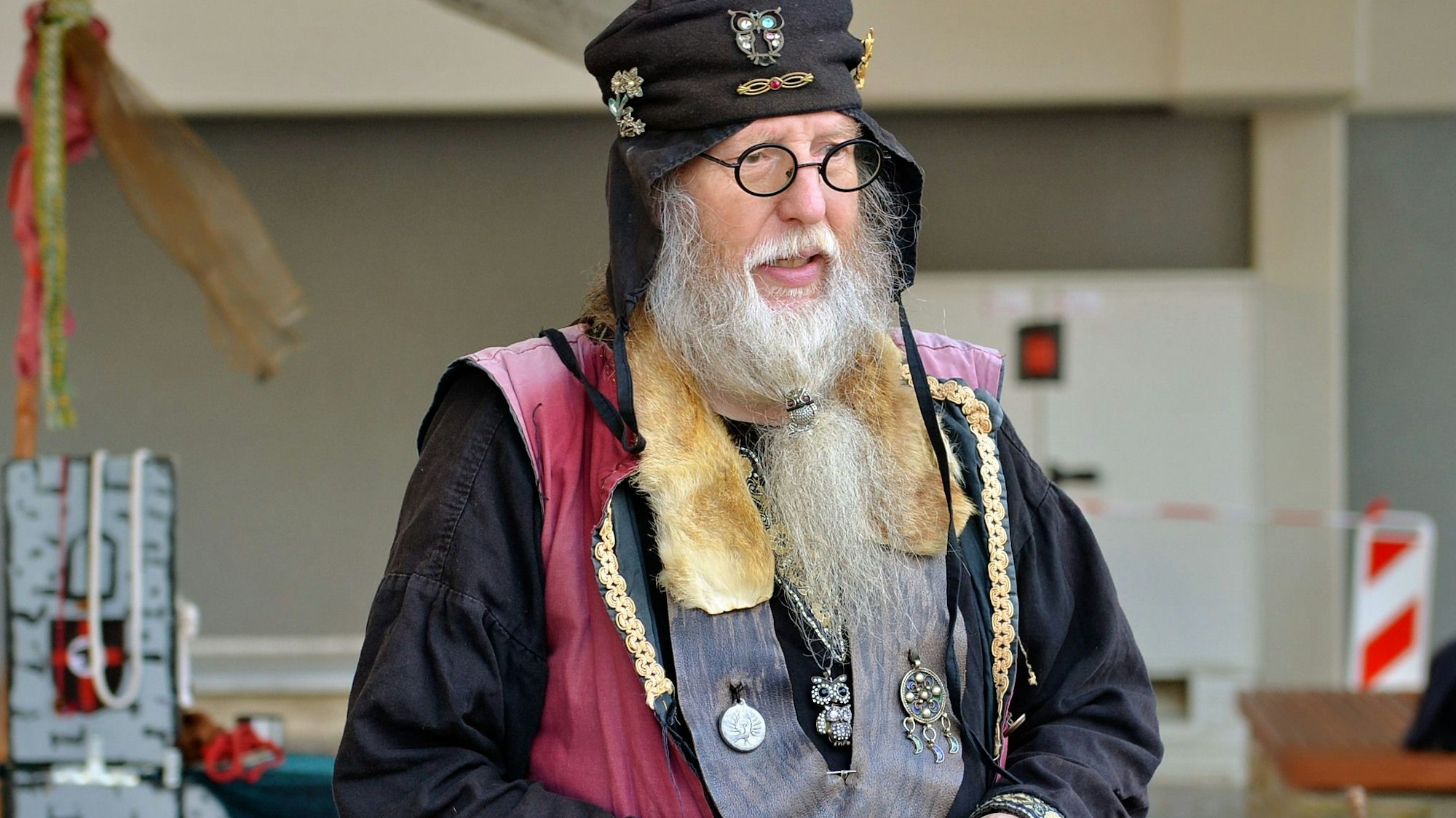 Ein Mann hat sich als mittelalterlicher Magier verkleidet und hält ein Buch.