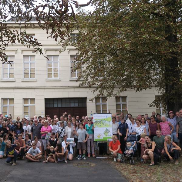 Ein große Gruppe Menschen hat sich vor dem ehemaligen Hauptgebäude des Lindweiler Hofs an der Rochusstraße versammelt.