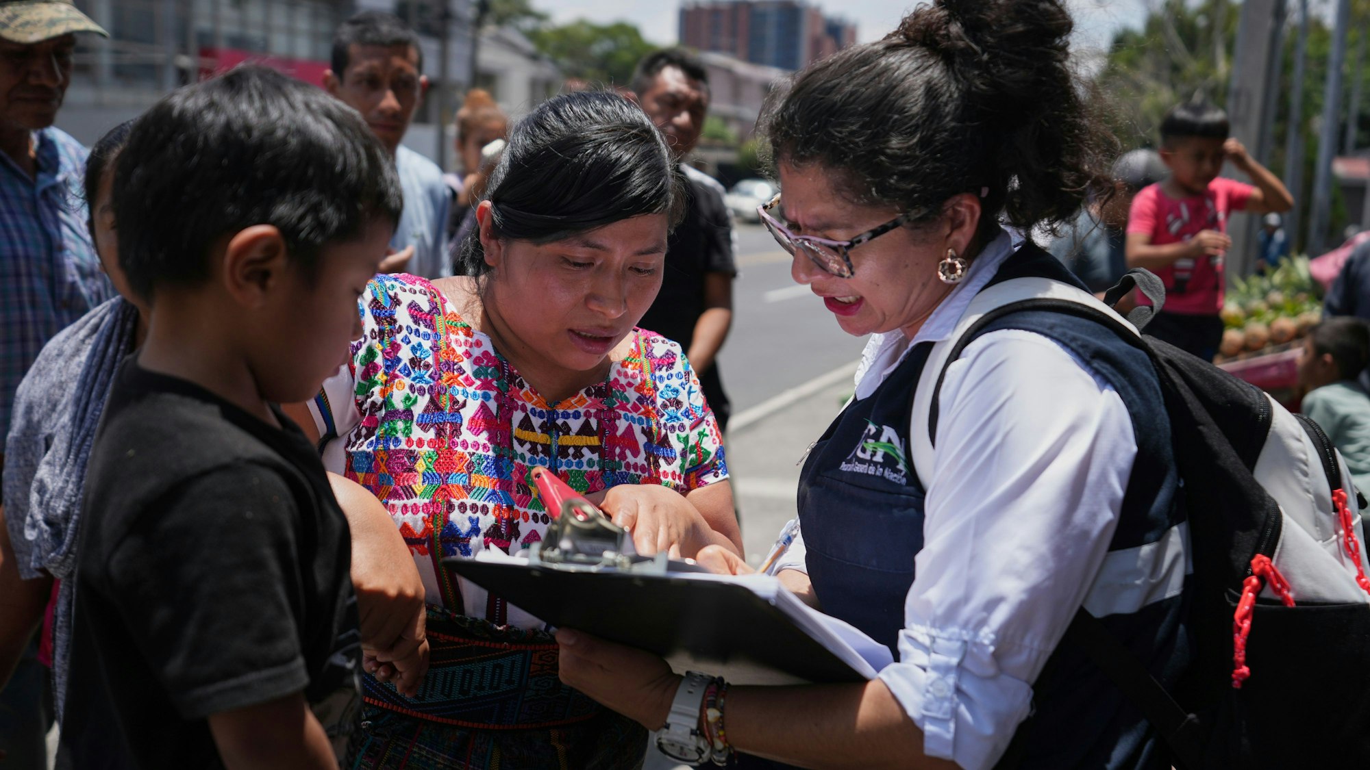 31.08.2025, Guatemala, Guatemala-Stadt: Eine Verwandte eines unbegleiteten Minderjährigen, der aus den Vereinigten Staaten überführt wurde, studiert vor dem internationalen Flughafen La Aurora in Guatemala-Stadt die Liste der Rückgeführten. Foto: Moises Castillo/AP/dpa +++ dpa-Bildfunk +++