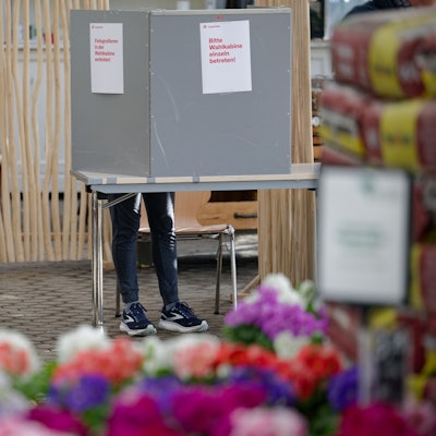 23.02.2025, Nordrhein-Westfalen, Köln: Eine Frau steht in einem Wahllokal in einem Gewächshaus eines Gartenbaubetriebs in Köln-Hahnwald hinter einer Wahlkabine. Am Sonntag findet die vorgezogene Wahl zum 21. Deutschen Bundestag statt. (zu dpa: «NRW wählt den Bundestag - höhere Wahlbeteiligung in Köln») Foto: Henning Kaiser/dpa +++ dpa-Bildfunk +++