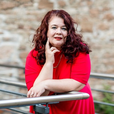 Eine Frau im roten Kleid lehnt auf einem Geländer.