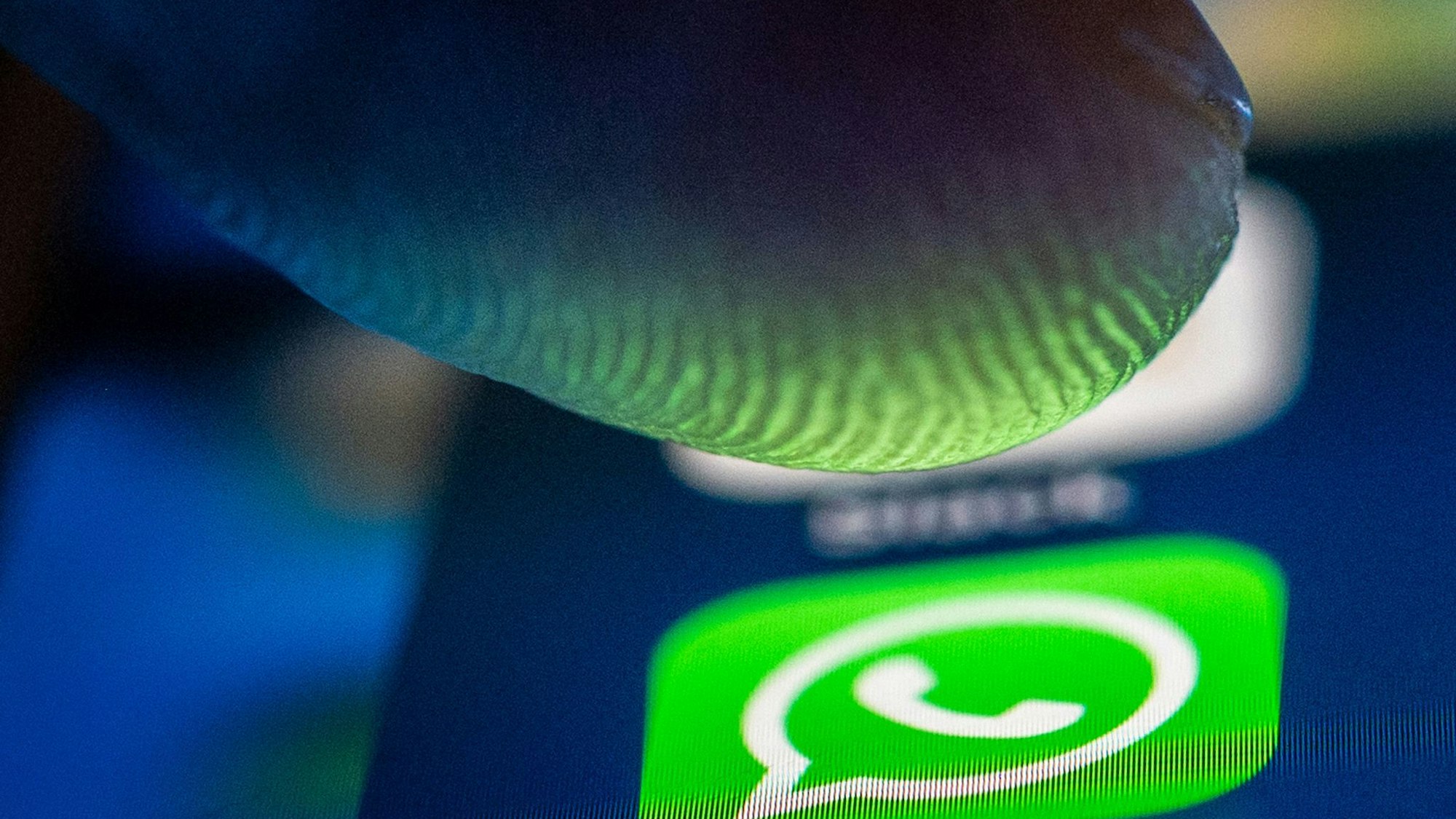 Ein Finger drückt auf einem Handy die Whatsapp-App.