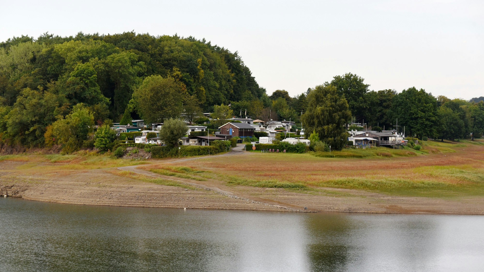 Das Foto zeigt den Campingplatz Käfernberg, im Vordergrund die Bevertalsperre, die derzeit viel zu wenig Wasser führt.