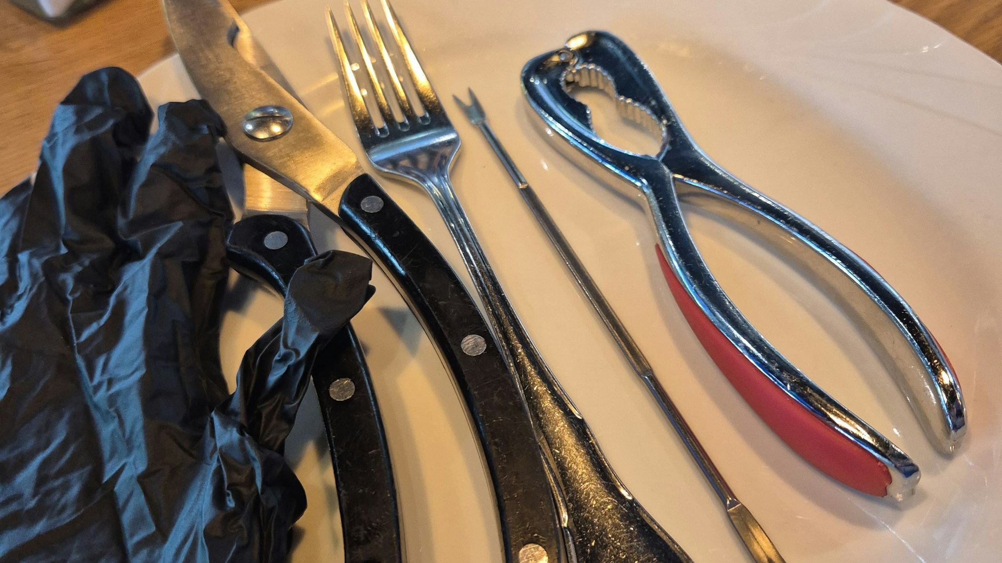 Werkzeuge wie Geflügelschere, Nussknacker und Fleischzieher werden benutzt, um eine Seafood Boil zu essen.