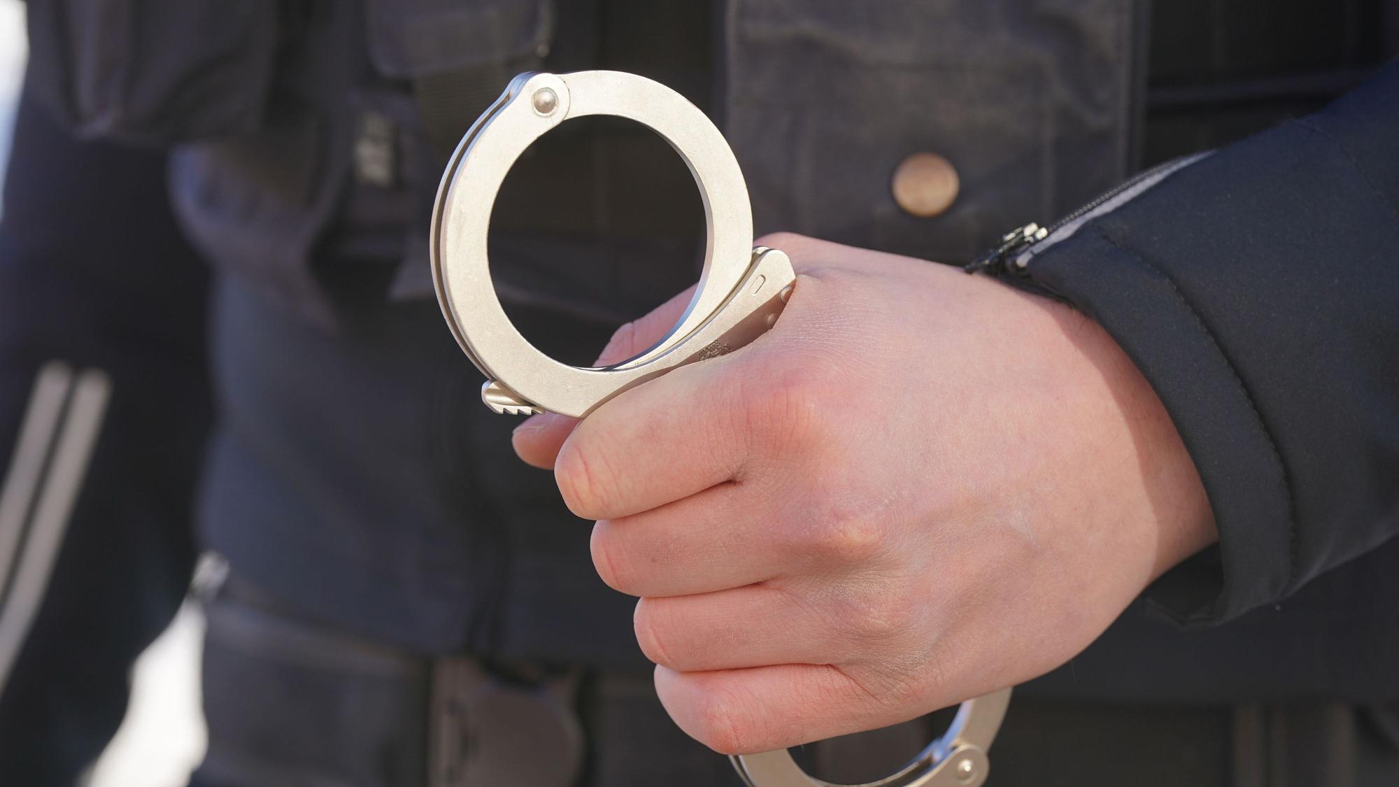 Ein Polizist hält Handschellen in der Hand.